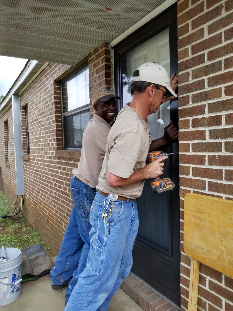 Maintenance workers installing a screen door